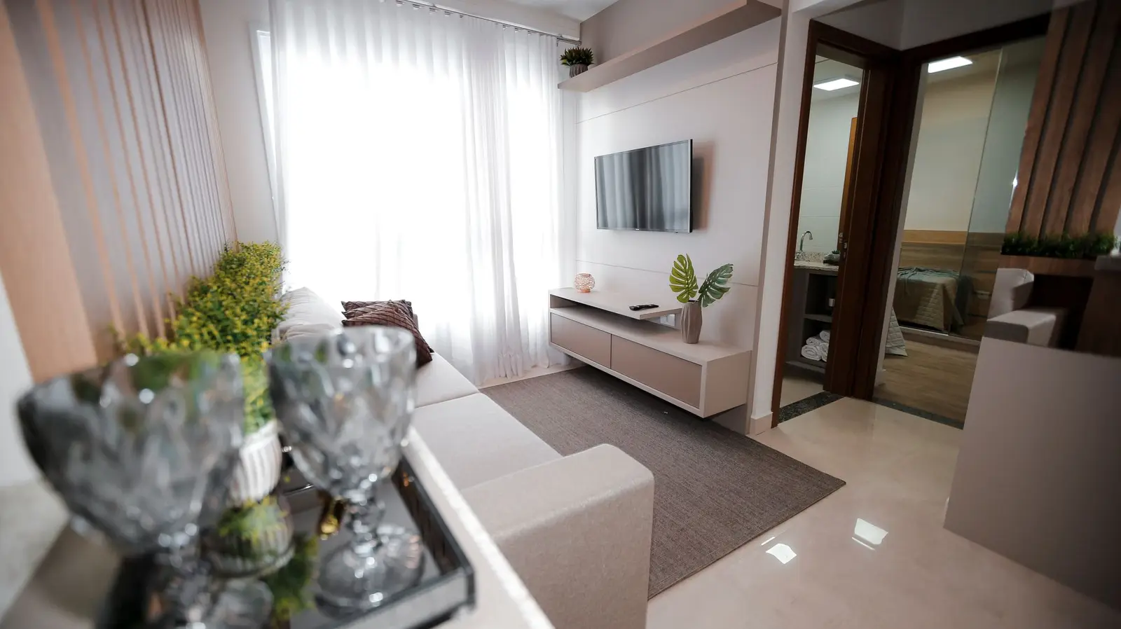 Sala com painel de TV e plantas junto à janela