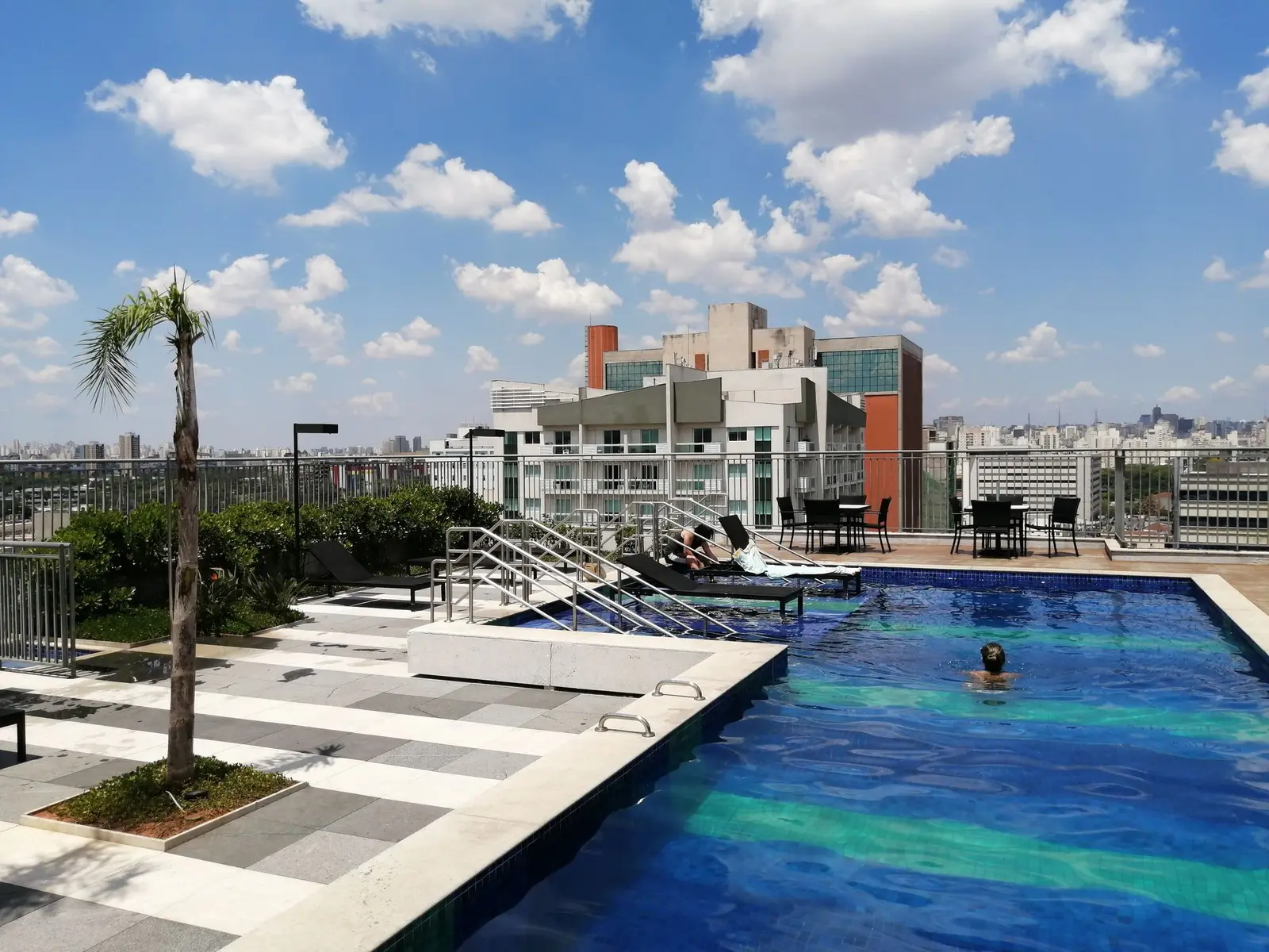 Piscina na cobertura do prédio, com deck e vista da cidade