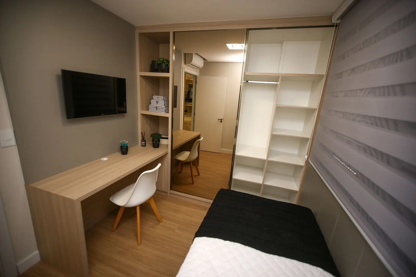 Quarto com escrivaninha, TV e armário aberto