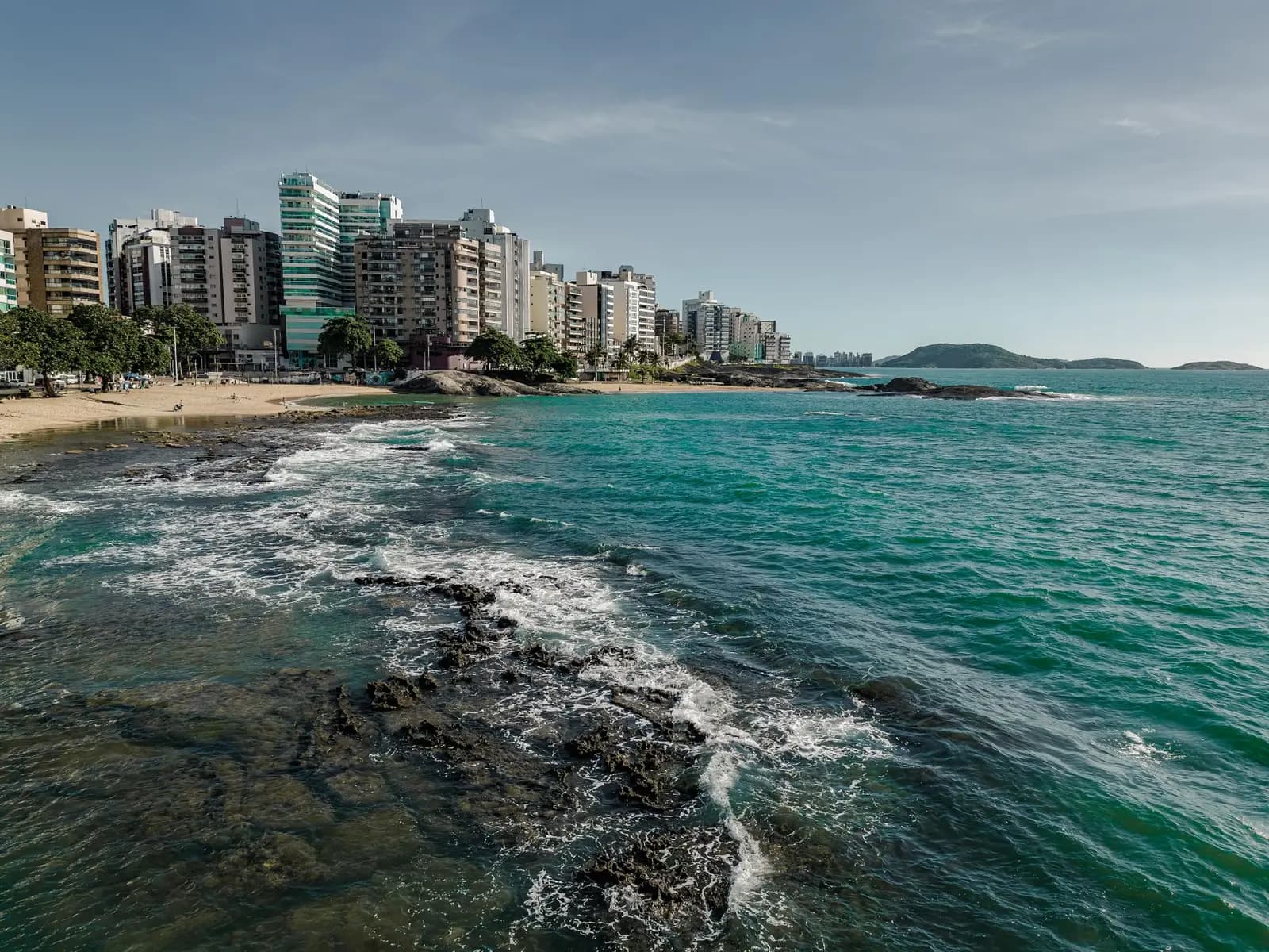 Costa de Guarapari com a cidade ao fundo e o mar verde-azulado