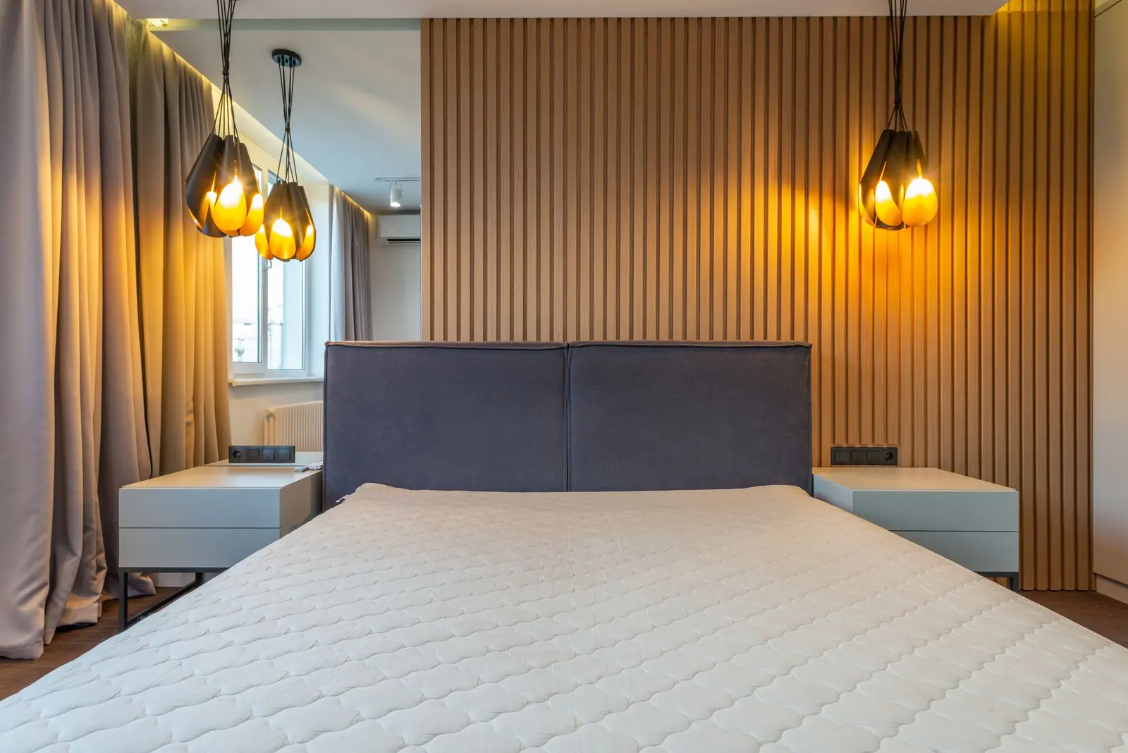 Quarto de casal com cabeceira estofada e painel ripado