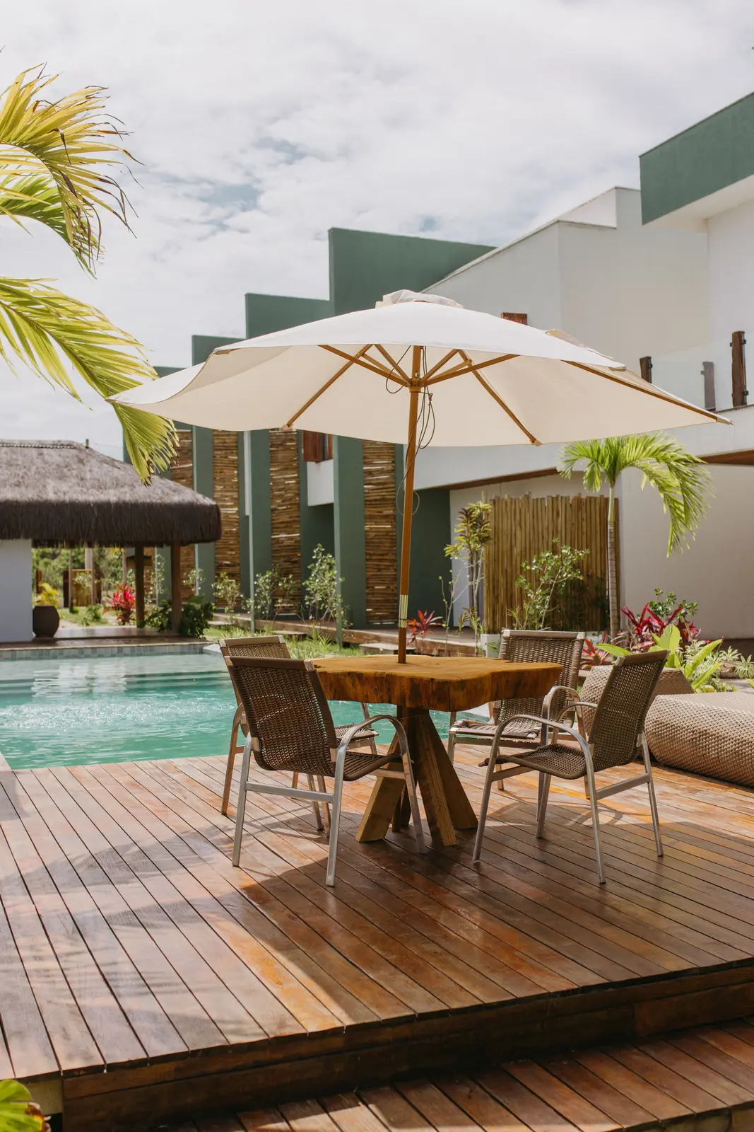 Deck com mesa e guarda-sol ao lado da piscina