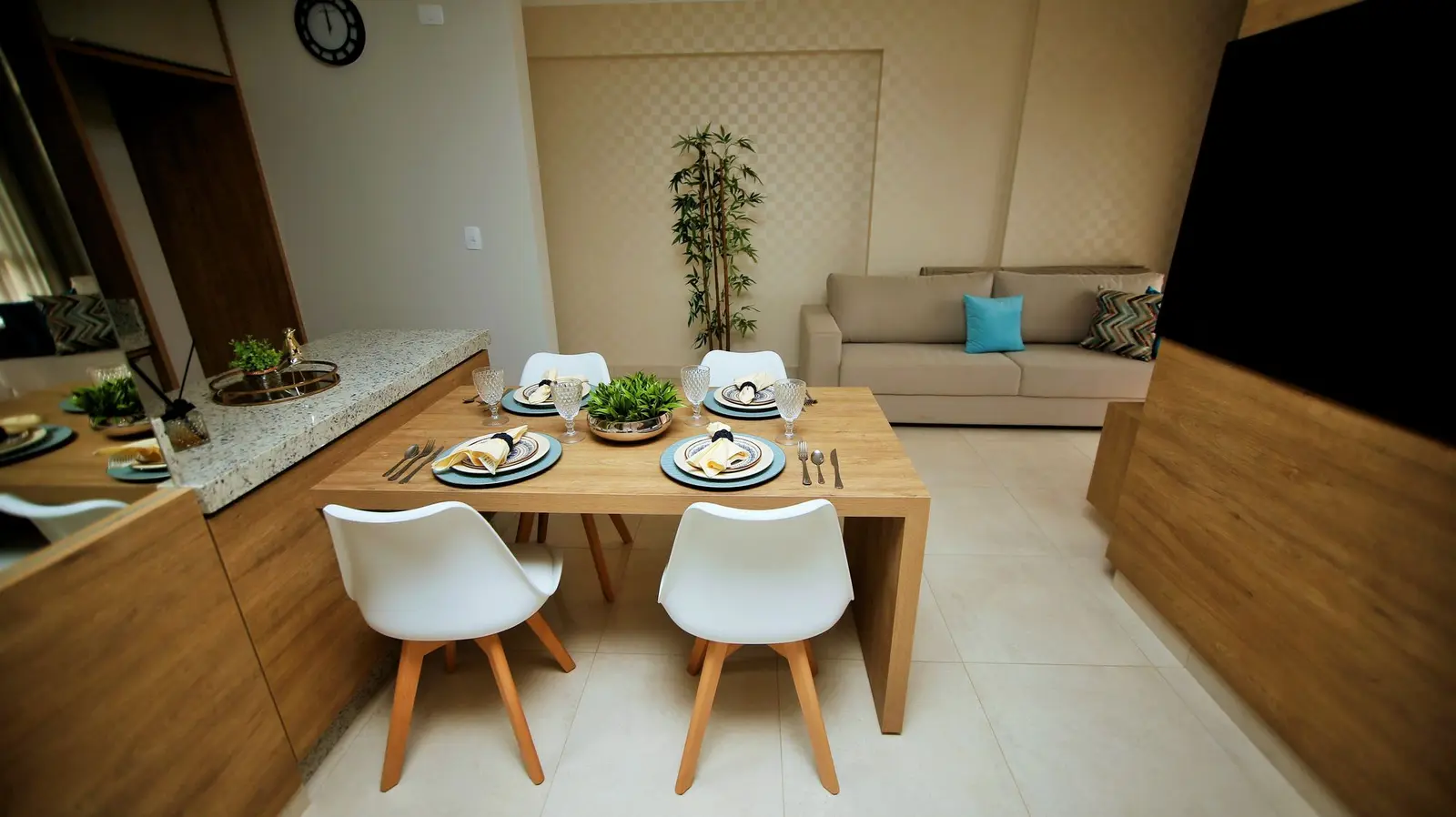 Sala com mesa de jantar de madeira e sofá ao fundo