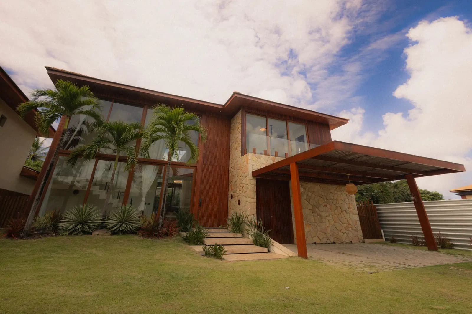Fachada da casa com gramado e coqueiros