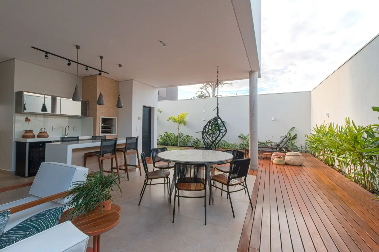 Terraço coberto com mesa de jantar, cozinha externa e deck