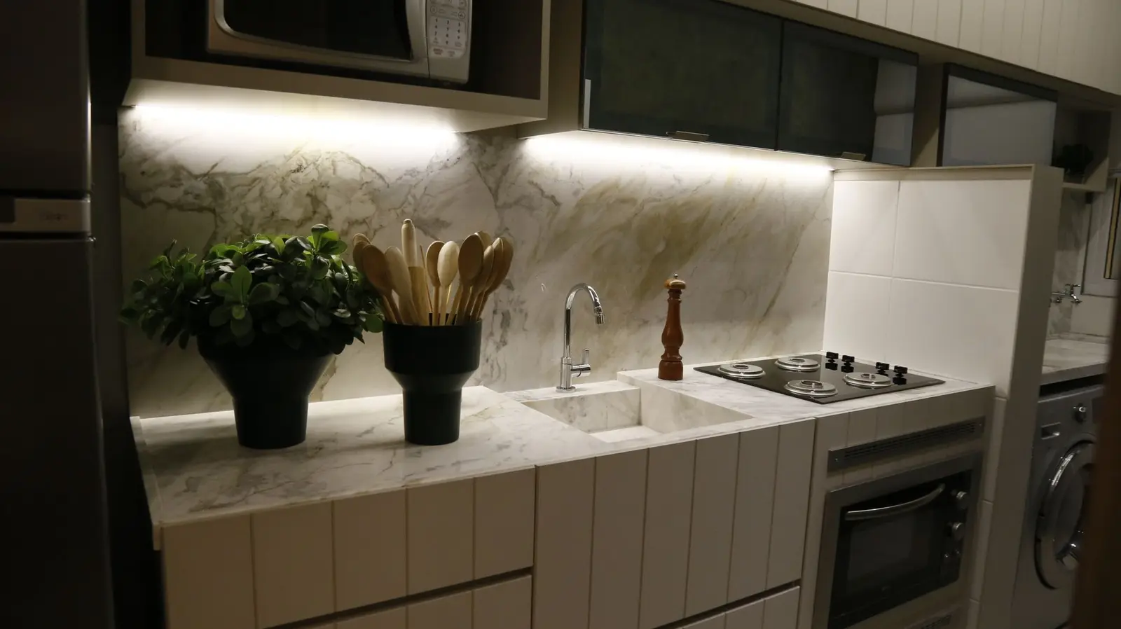 Cozinha compacta com bancada de mármore e cooktop