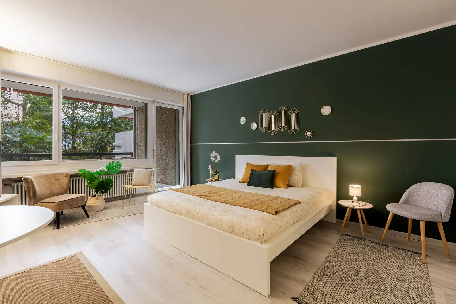 Cama de casal junto à parede verde, com luz natural