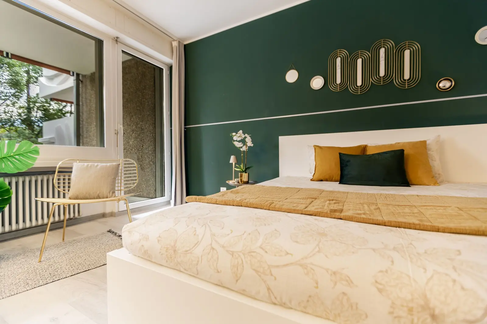 Cama de casal com almofadas mostarda e porta de vidro ao lado