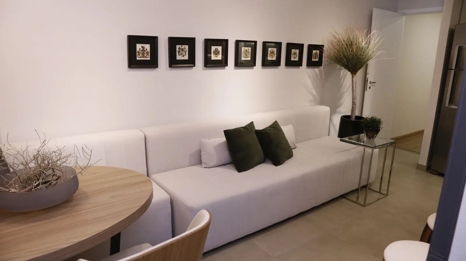 Sala com sofá branco e quadros pequenos na parede