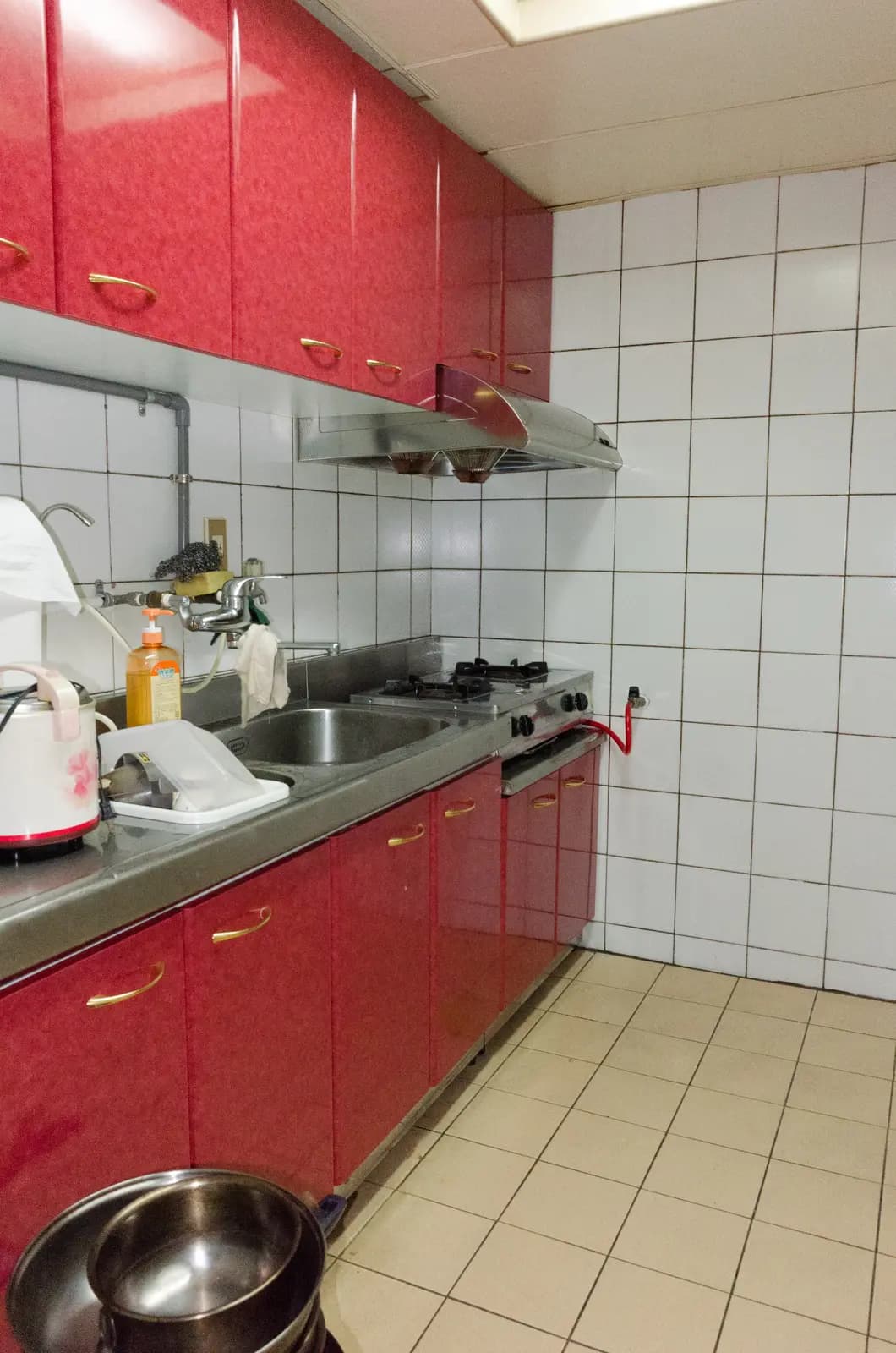 Cozinha com armários vermelhos e azulejos brancos