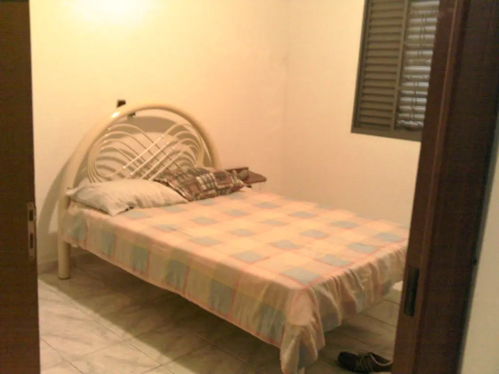 Quarto de casal com cama de ferro e janela veneziana