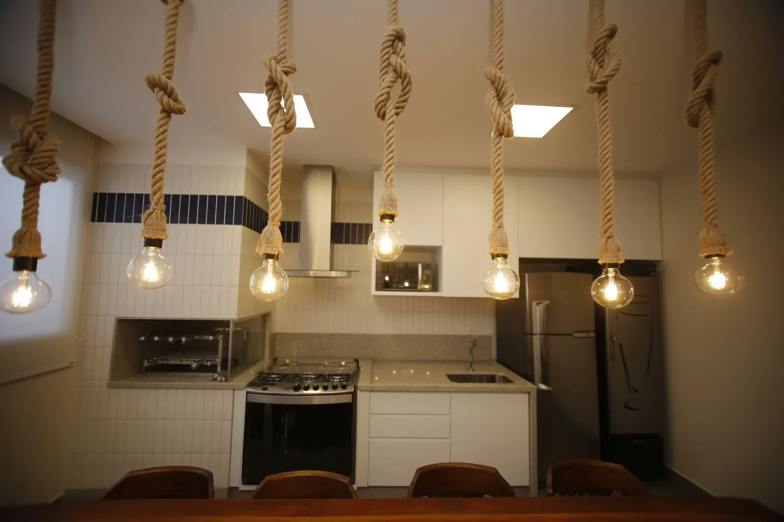 Cozinha com fogão, coifa e pendentes de corda