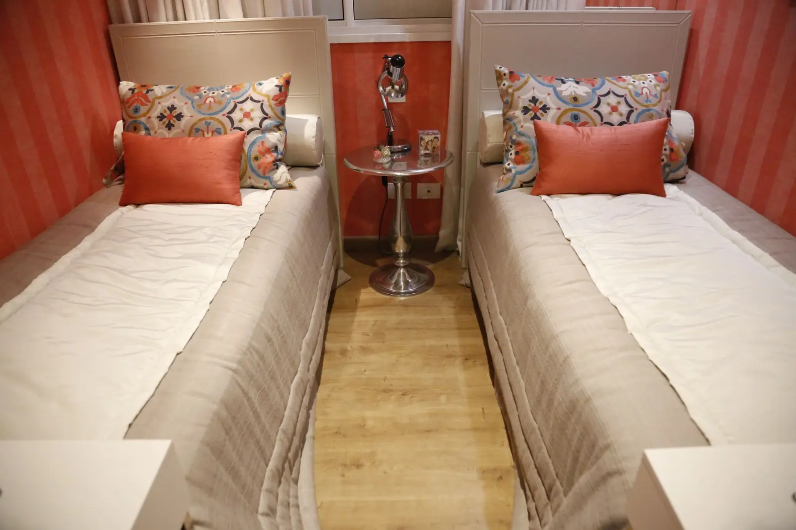 Quarto com duas camas de solteiro e almofadas estampadas