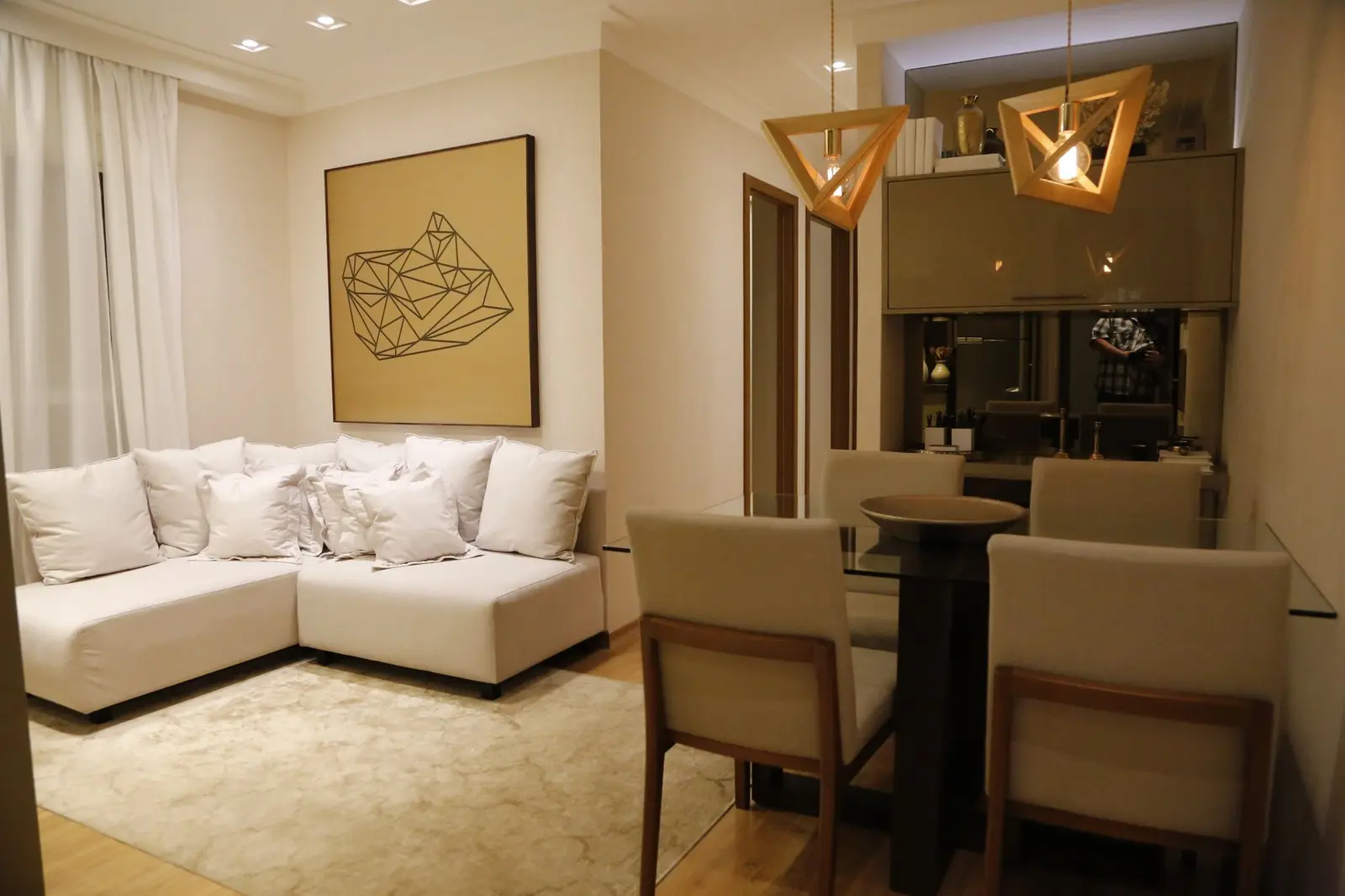 Sala com sofá em L e mesa de jantar com pendentes de madeira