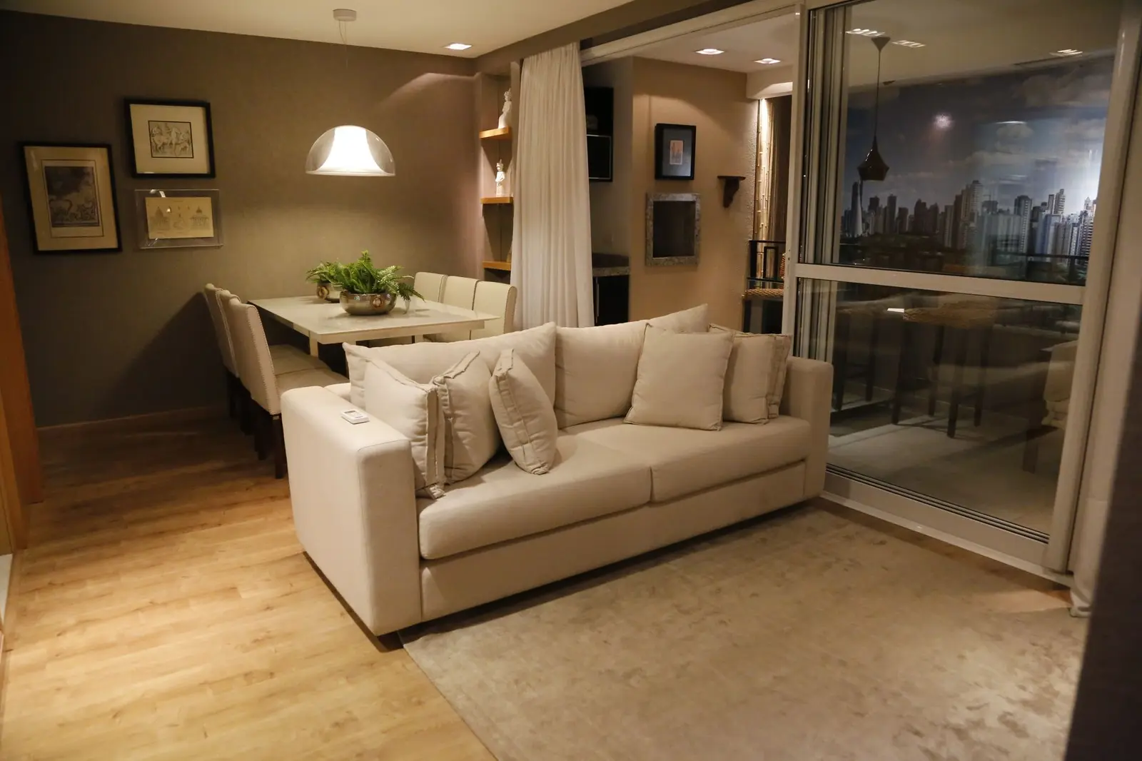 Sala com sofá claro e porta de vidro para a sacada